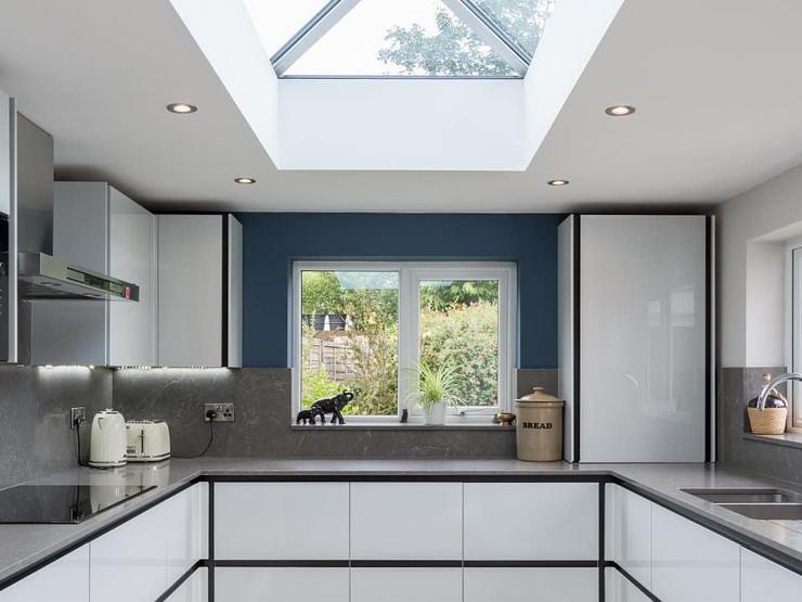 A kitchen extension idea using a grey gloss kitchen with a handleless design, dark-grey worktops, and black profiles