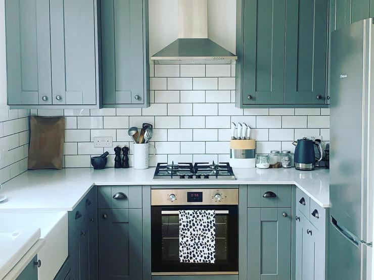 Grey shaker kitchen in a u-shaped design, with a matt finish, black cup handles and white quartz worktops.