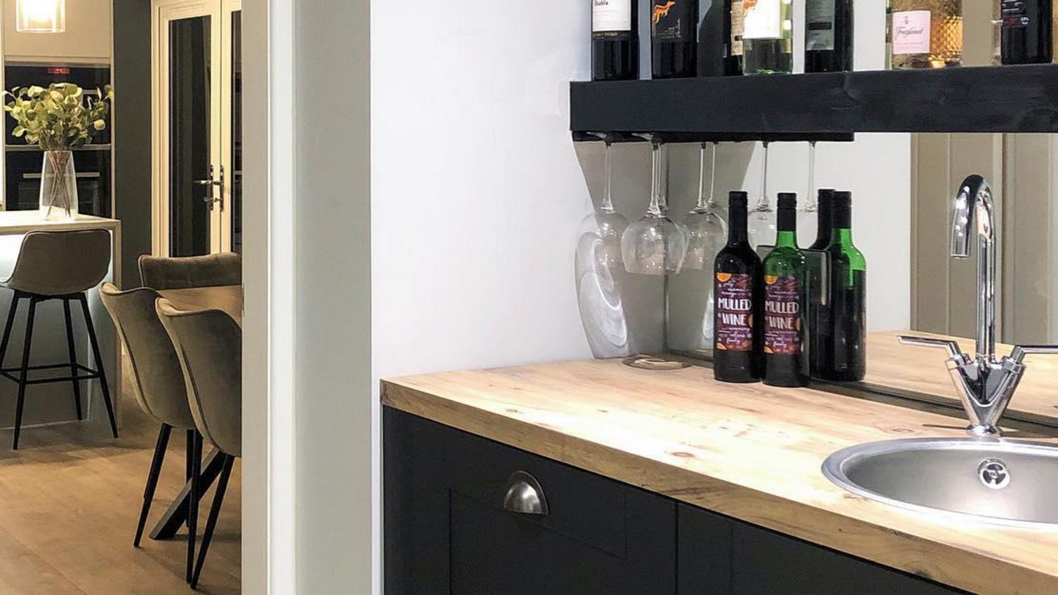 At-home bar idea with charcoal shaker cupboards, solid oak worktop, silver inset sink, and open shelving.