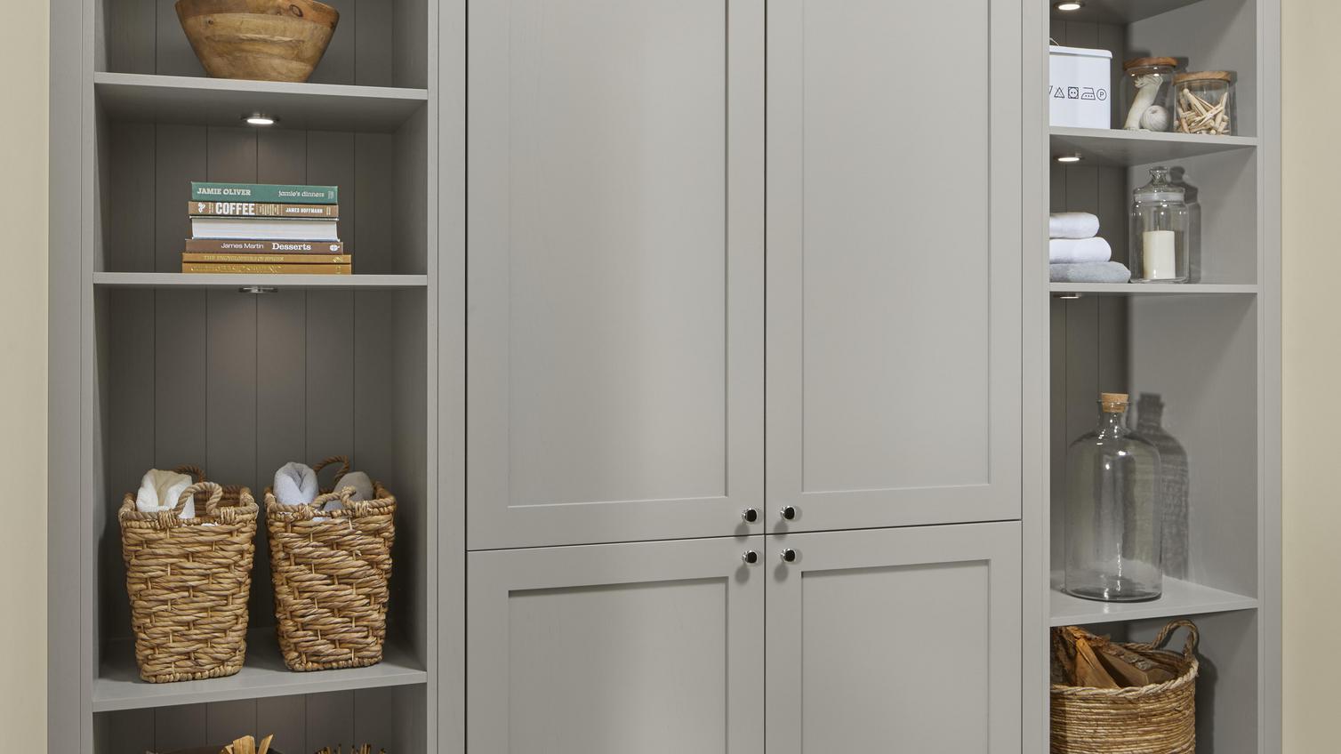 Chilcomb pebble open shelving unit with two middle closed doors, wall panelling and decorative objects.