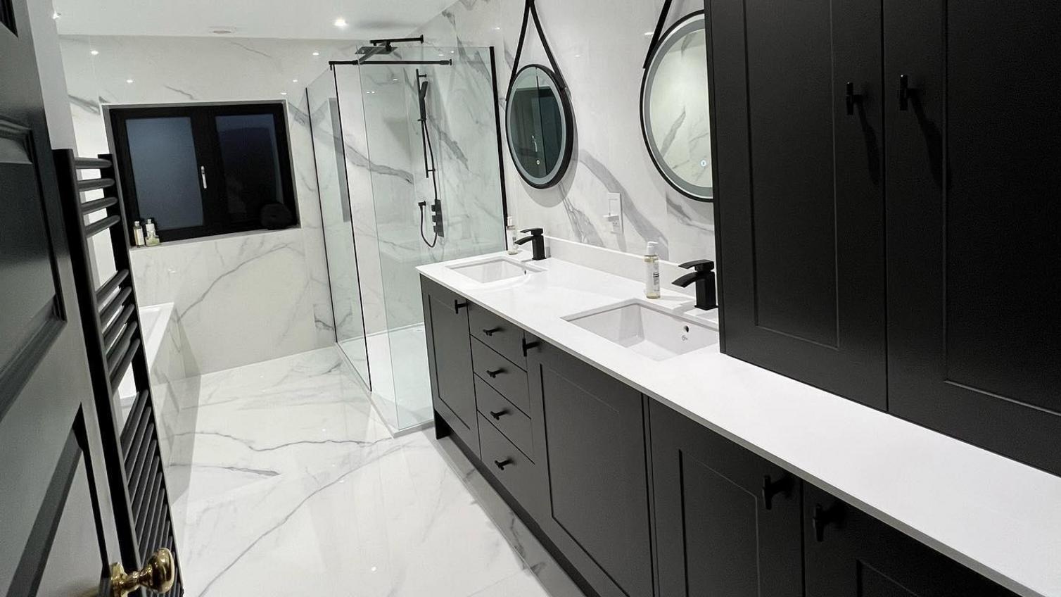 Monochrome bathroom idea featuring black shaker cupboard doors and white worktops. Has black handles and an undermount sink.