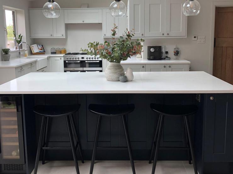 Navy island with white worktop and black bar stools