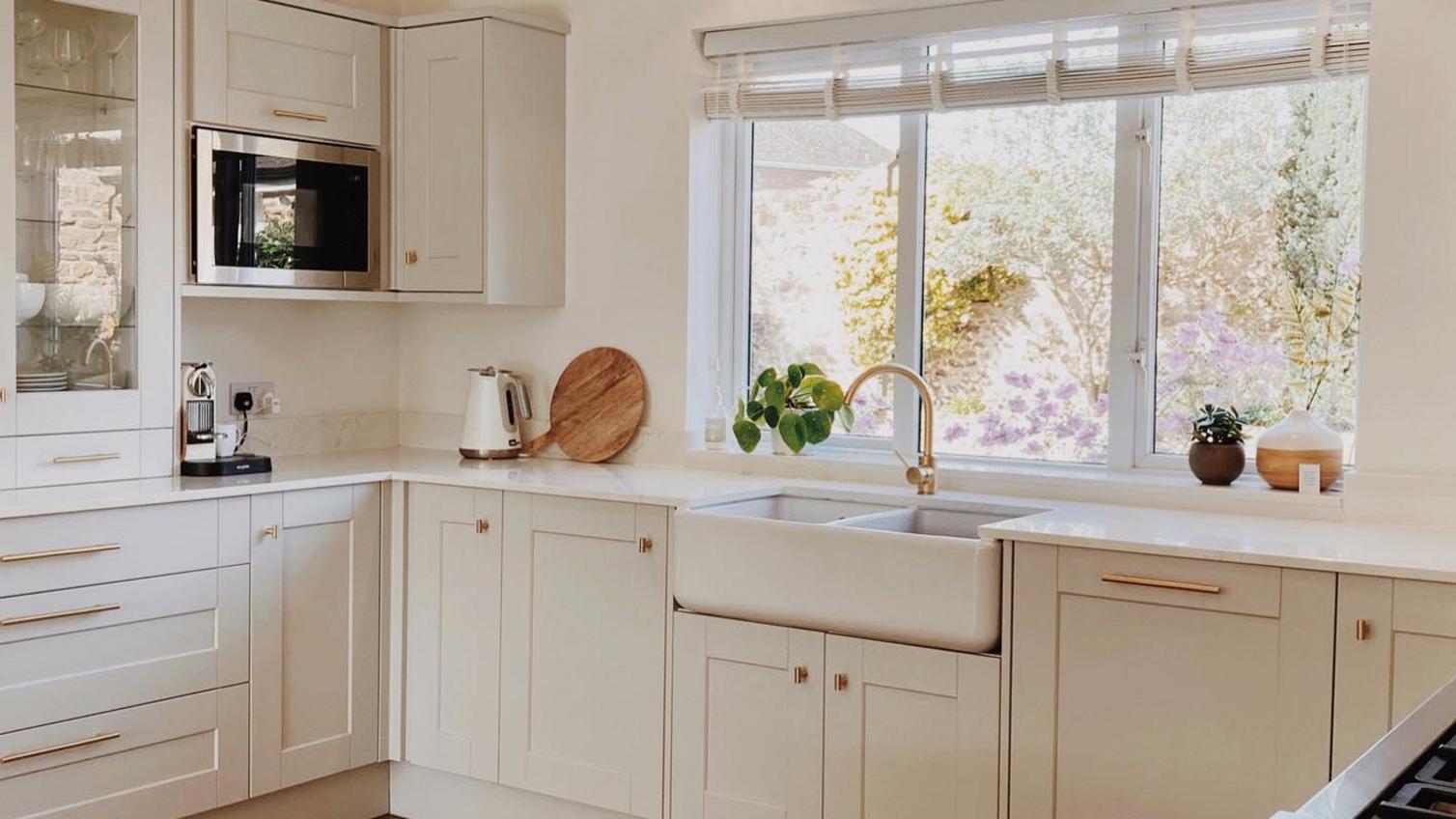 U-shaped cream kitchen idea using shaker doors and brass handles. Includes a double Belfast sink and oak chevron flooring.