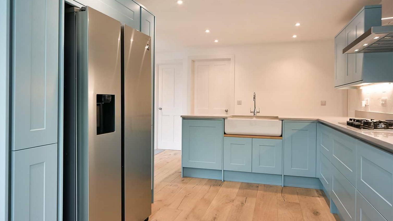 Blue painted kitchen idea using shaker cupboard doors. Includes a Belfast sink and a silver American fridge.