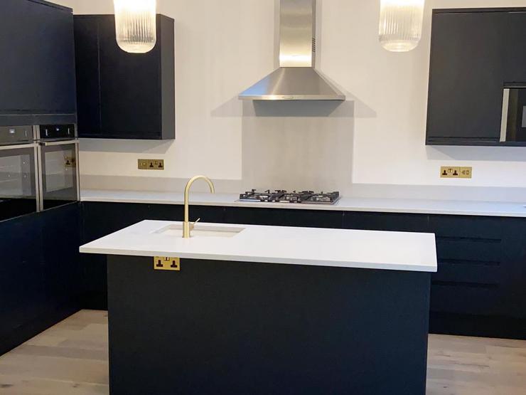 Navy shaker L-shaped kitchen idea with an island. Includes a silver extractor, white worktops, and a brass tap.