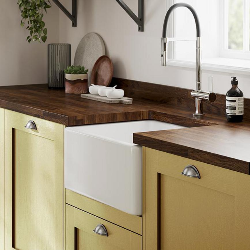 A mustard yellow kitchen using Chilcomb Paintable, styled with wooden worktops, a ceramic sink and cabinet cup handles.
