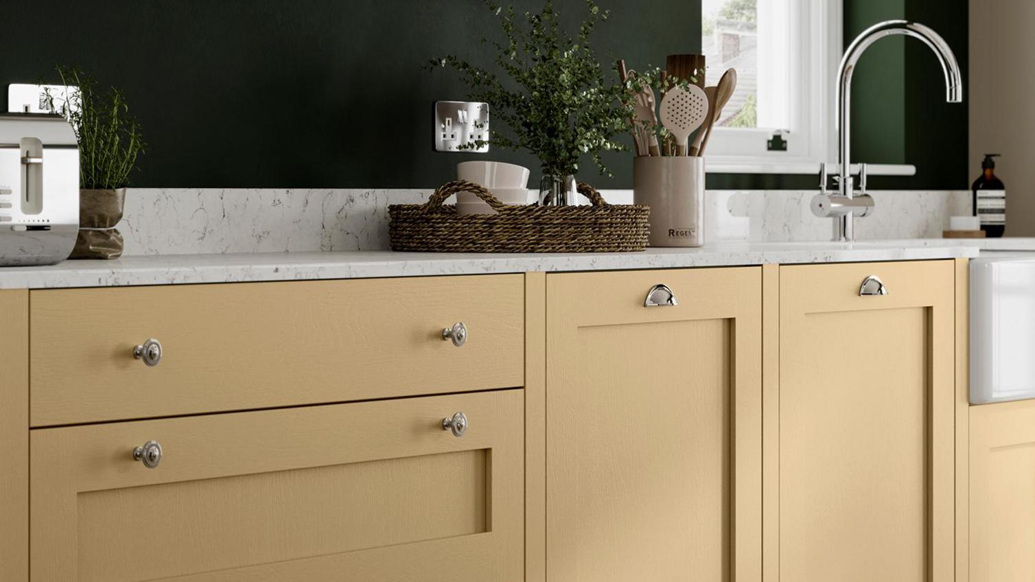 Yellow paintable kitchen idea with a shaker cupboards, silver knob handles, white marble worktop and a silver mixer tap.