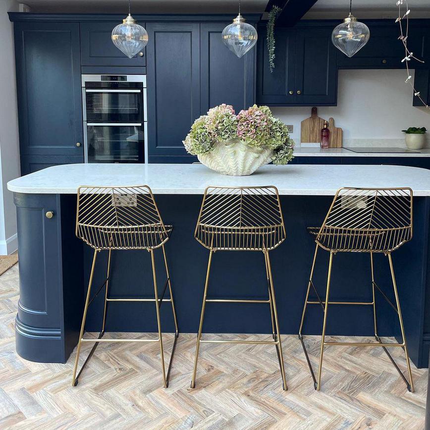 Charcoal shaker kitchen design with an island, quartz worktop, brass knob handles and flowers.