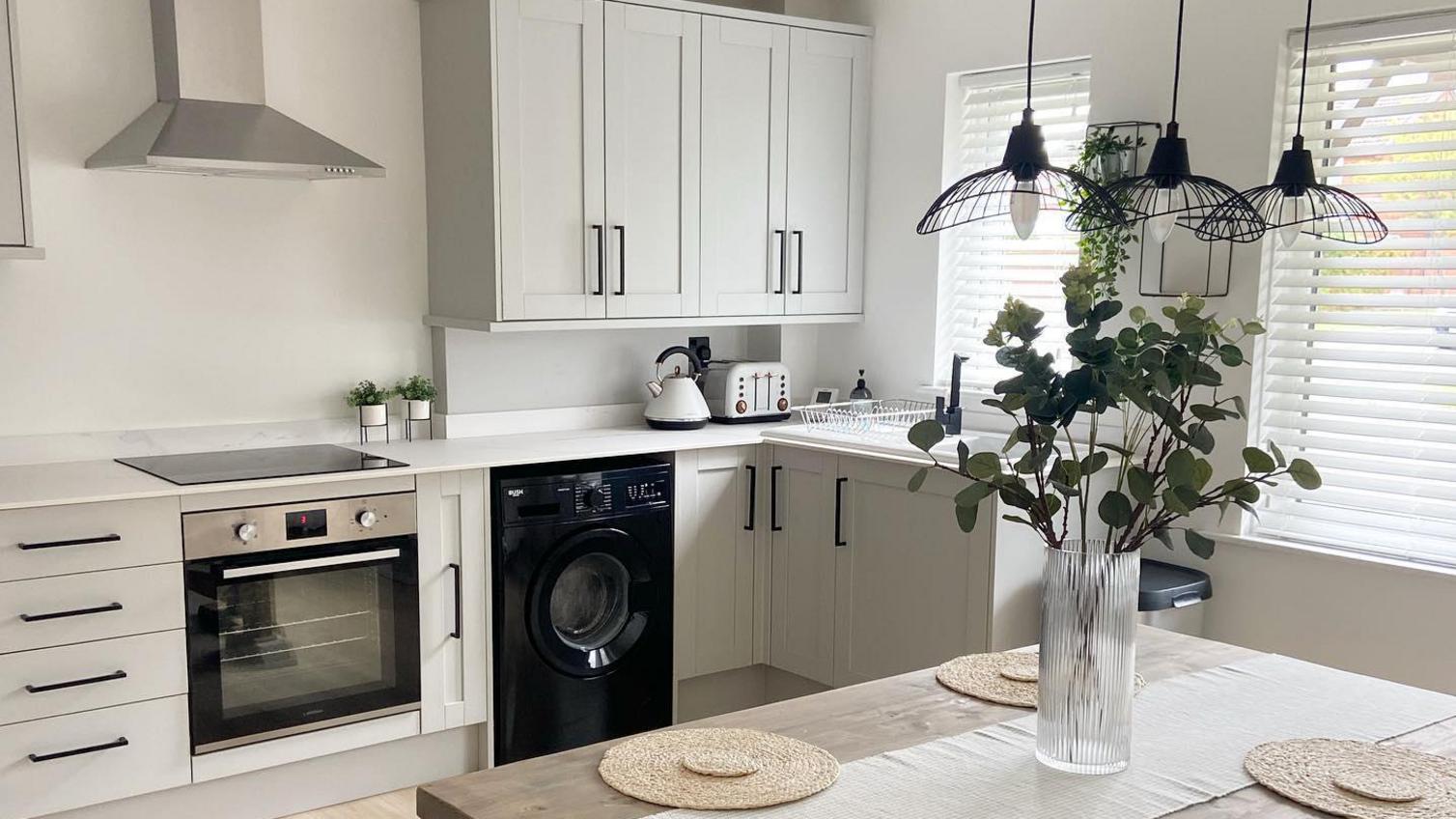 Scandi shaker kitchen makeover using Witney dove-grey cupboard doors. Includes timber floors and black, d-shape handles.