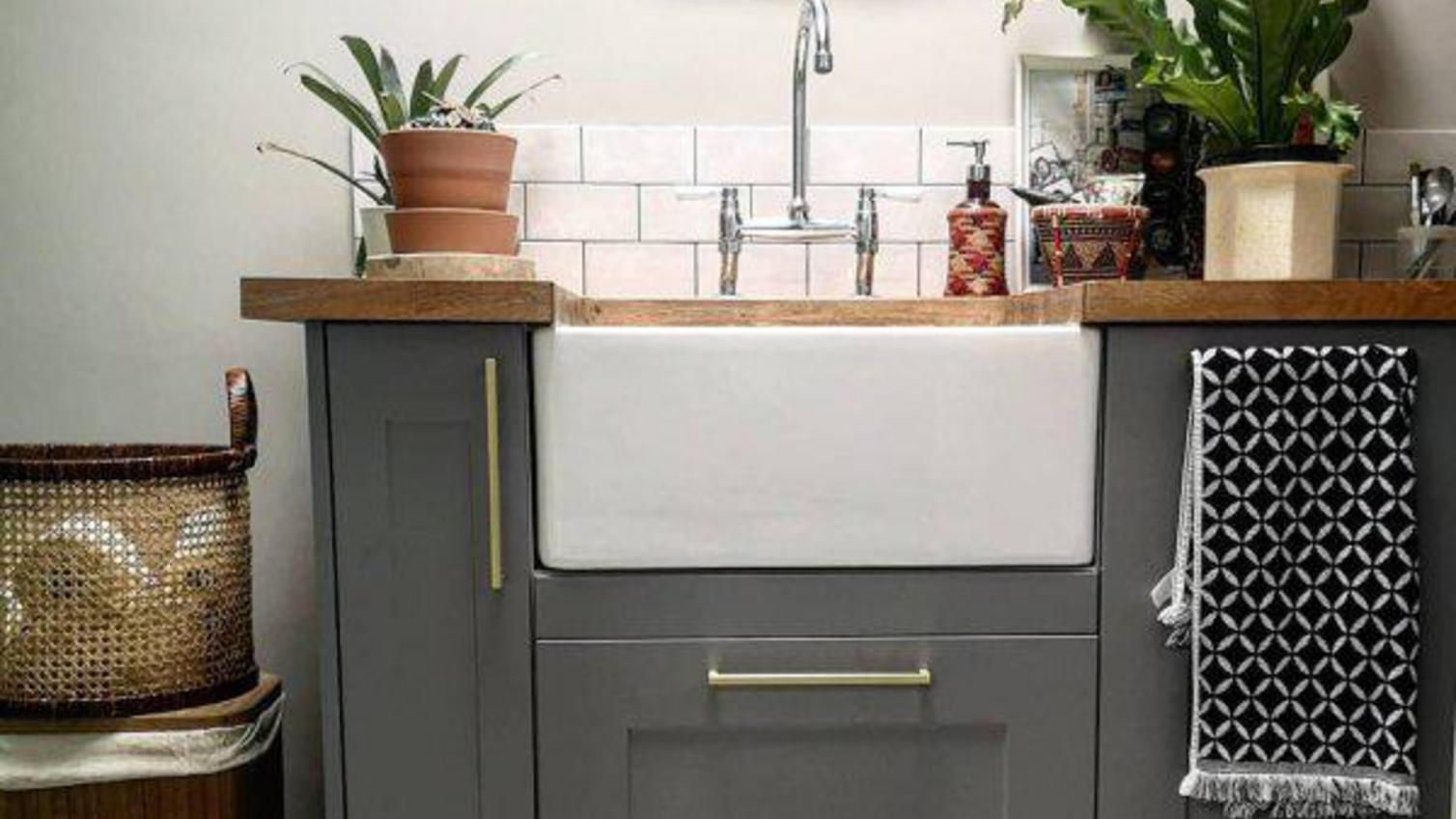 A small utility room area in a white, grey, and timber worktop
