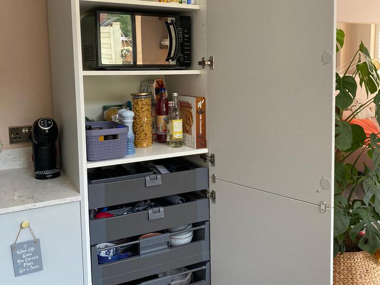 Larder tower in a grey kitchen with shelving and four drawers at the bottom.