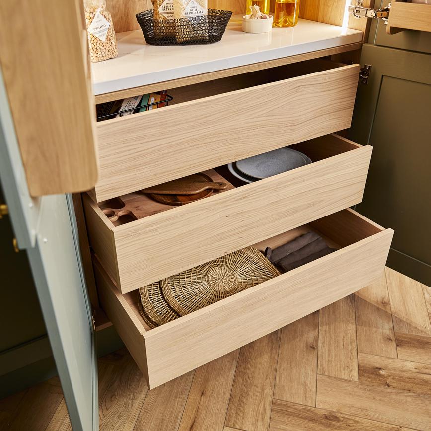 Deep oak internal drawers inside a sage green shaker pantry unit, with place mats and accessories shown in the drawer.