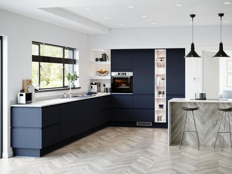 A sophisticated blue kitchen idea with integrated handle doors, white worktops, and chevron floors in a peninsular layout.