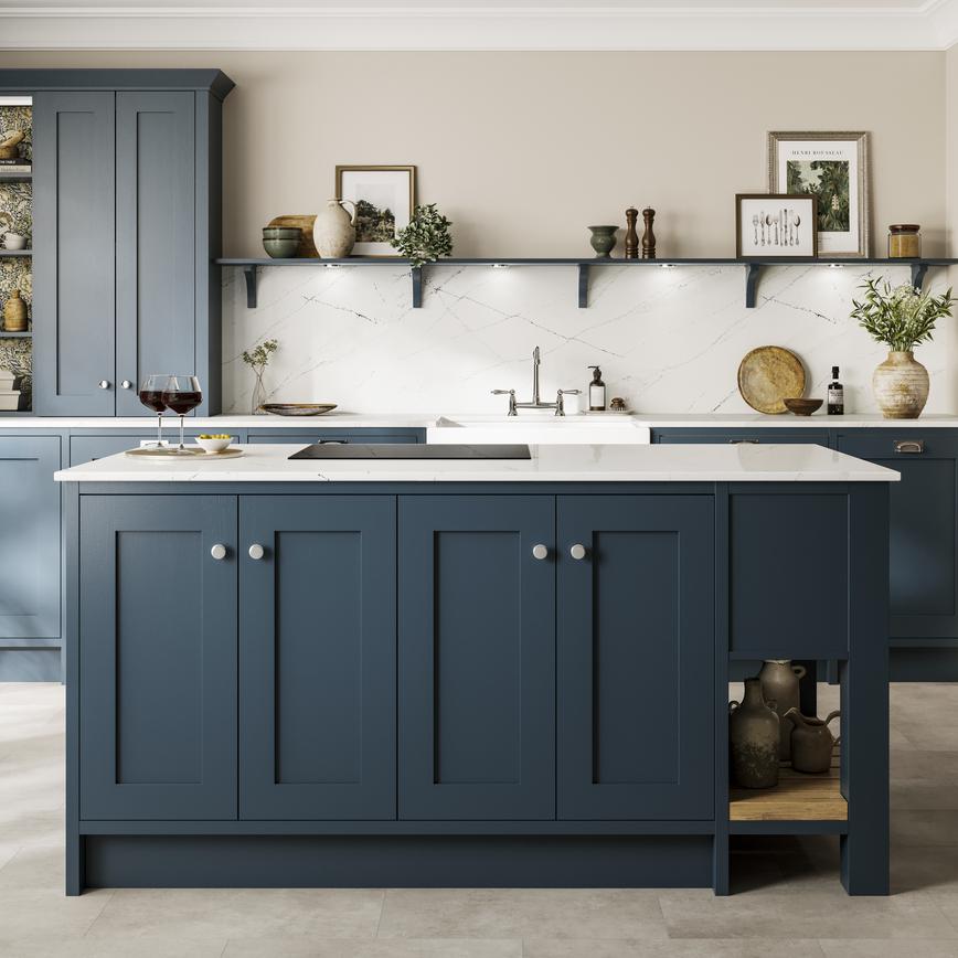 A classic kitchen with in-frame, blue shaker doors, white worktops, chrome knobs, and a black hob in an island layout. 