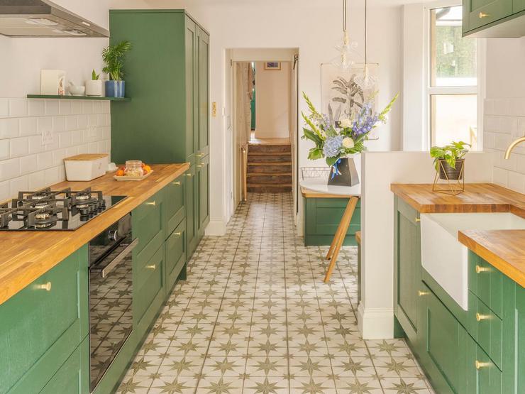Green shaker kitchen with brass handles and tap, and wood worktop