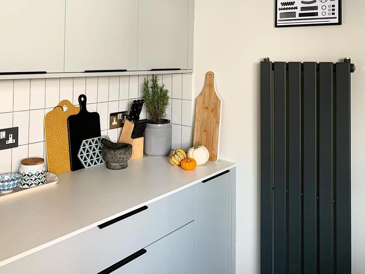 Grey slab kitchen with thin black handles, featuring matt doors and a white worktop. With white rectangular tiled backboard.