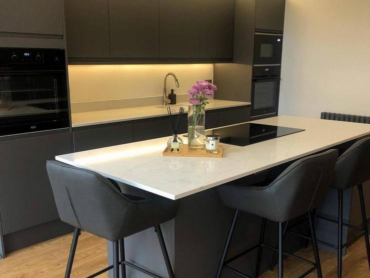 Charcoal kitchen design with matt integrated handles and an island in the centre, with a white quartz worktop.