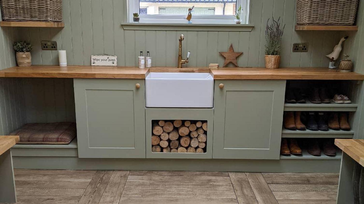 Green Belfast sink cabinets used as a boot room storage idea for shoe shelves and storing firewood.