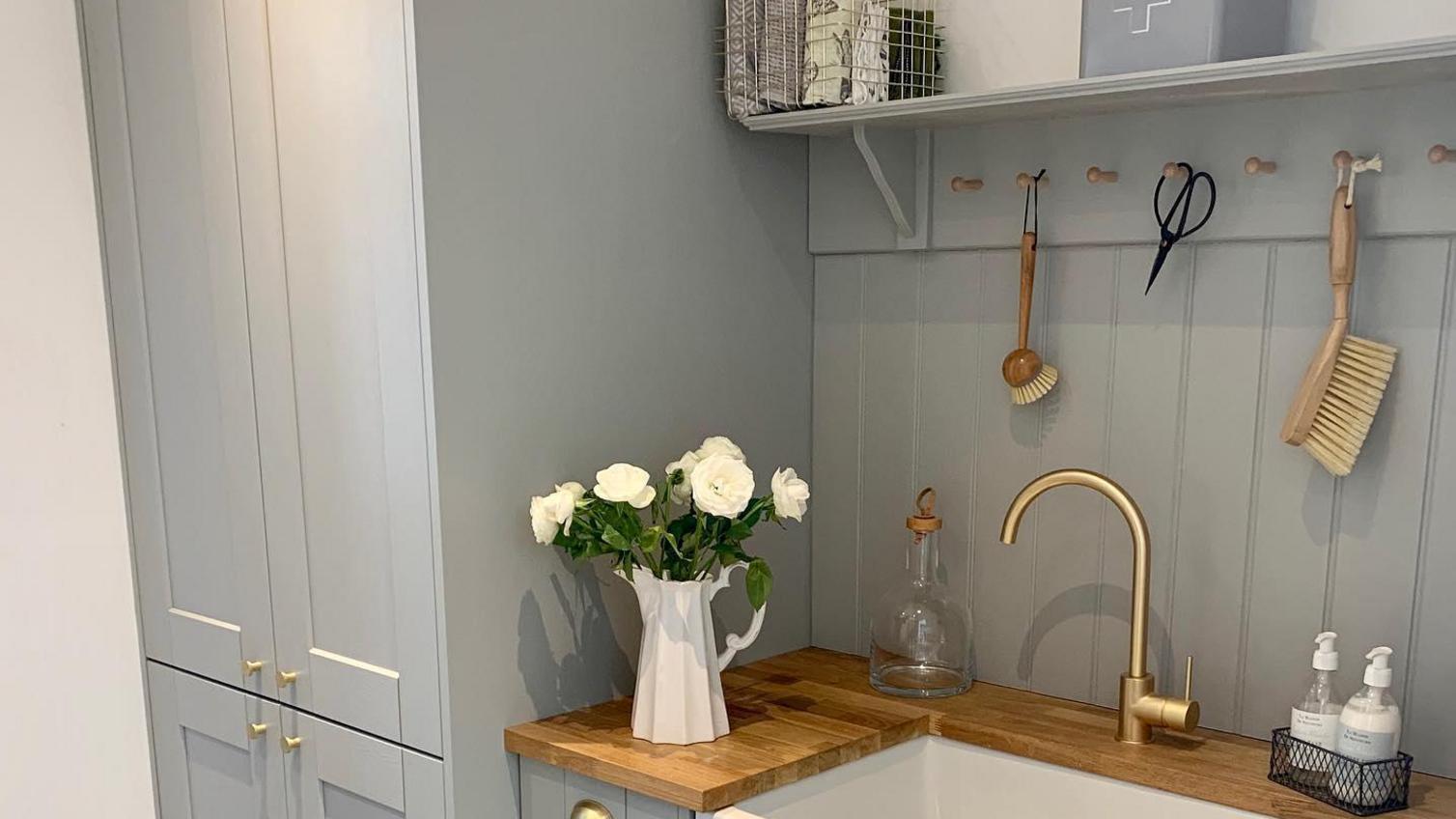 Grey shaker utility room idea with gold tap and handles, wood worktop, and wall pannelling.