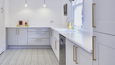 Large utility room idea with light-grey shaker doors, white worktops, gold bar handles and chevron tile floors
