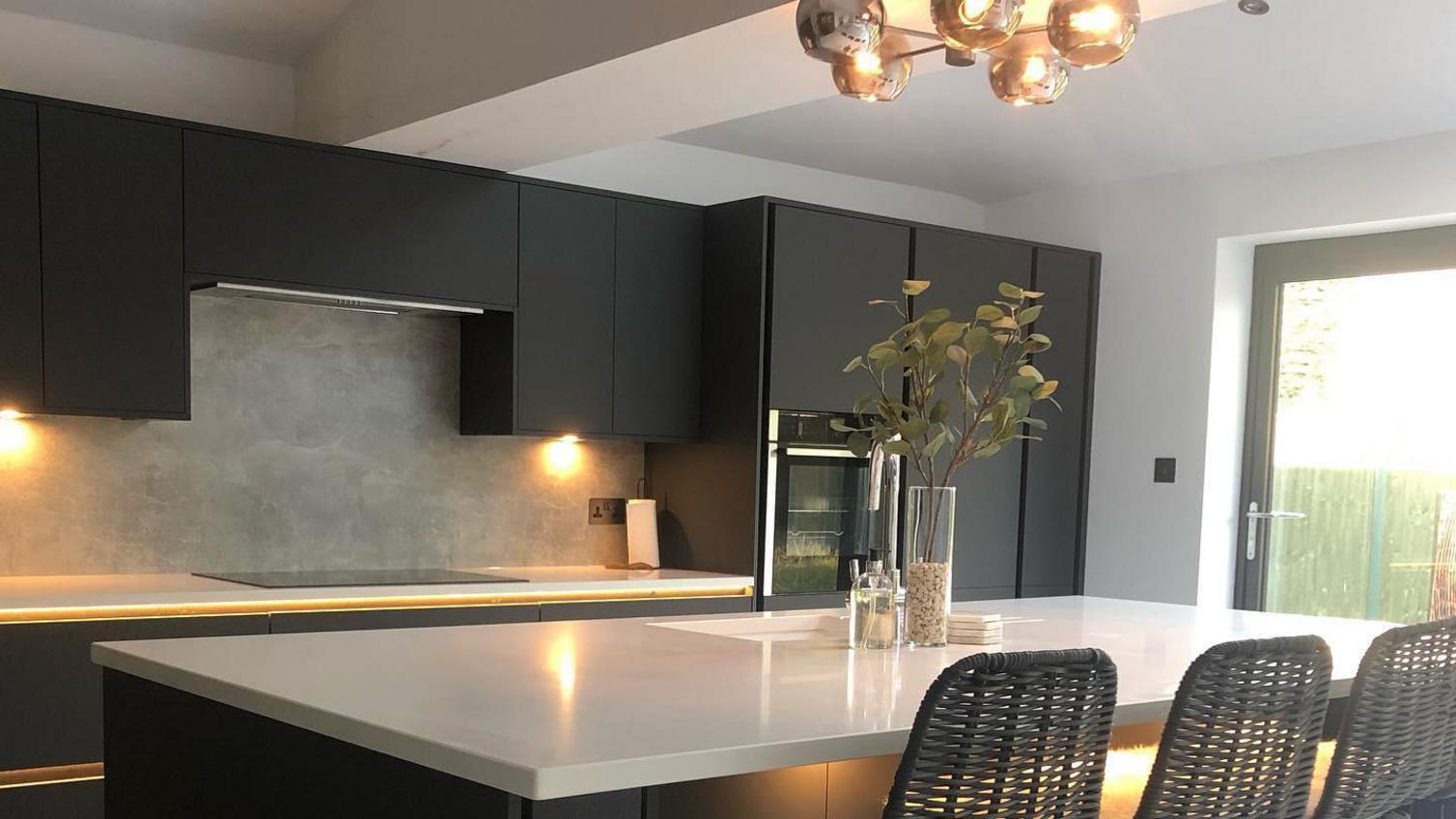 Black handleless kitchen with stone worktops and downlights for lighting