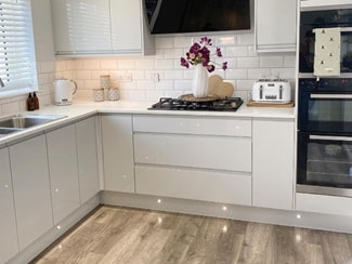 White gloss kitchen with wood-effect flooring and plinth lighting