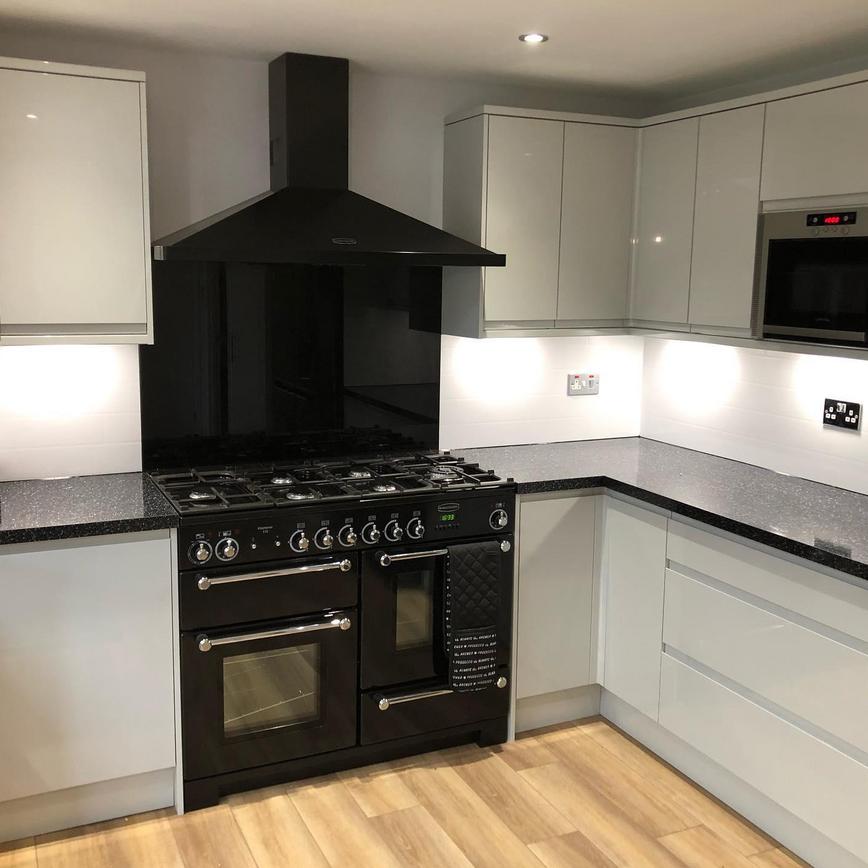 Gloss white kitchen with a large black Rangemaster range cooker and gas hob