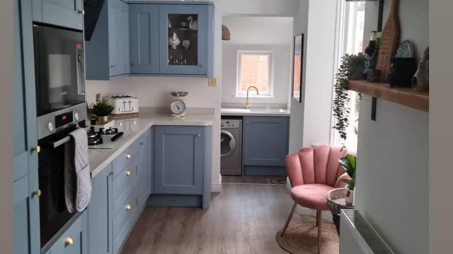 Blue shaker kitchen idea in a single wall layout with brass cup handles, beige worktops, and built in appliances.