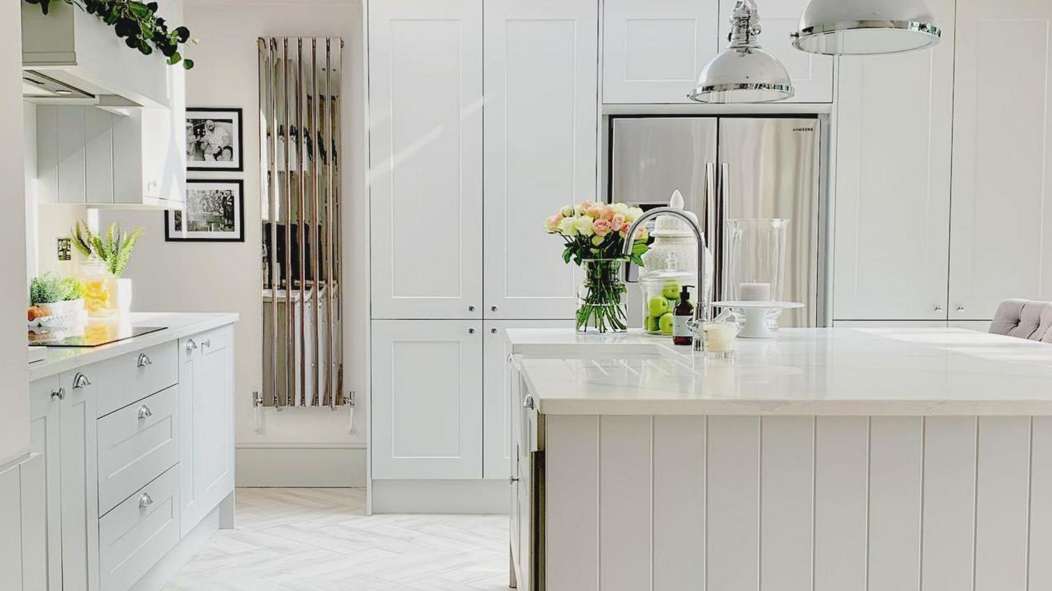 Light grey classic kitchen idea with island layout, panelling, chevron flooring and chrome fixtures.