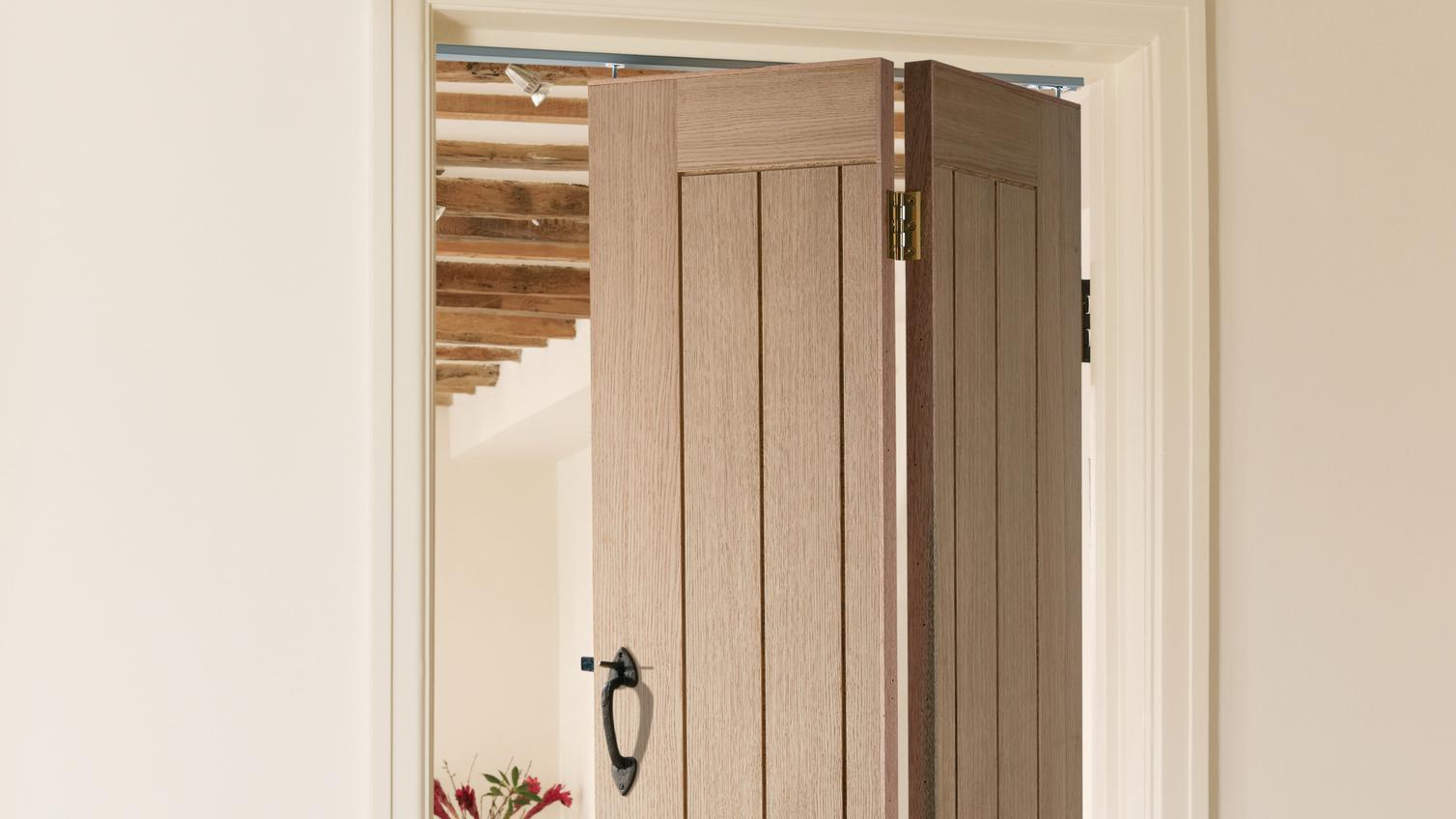 Holdenby oak bi-fold door, fitted in a white frame with a black catch-style rustic handle.