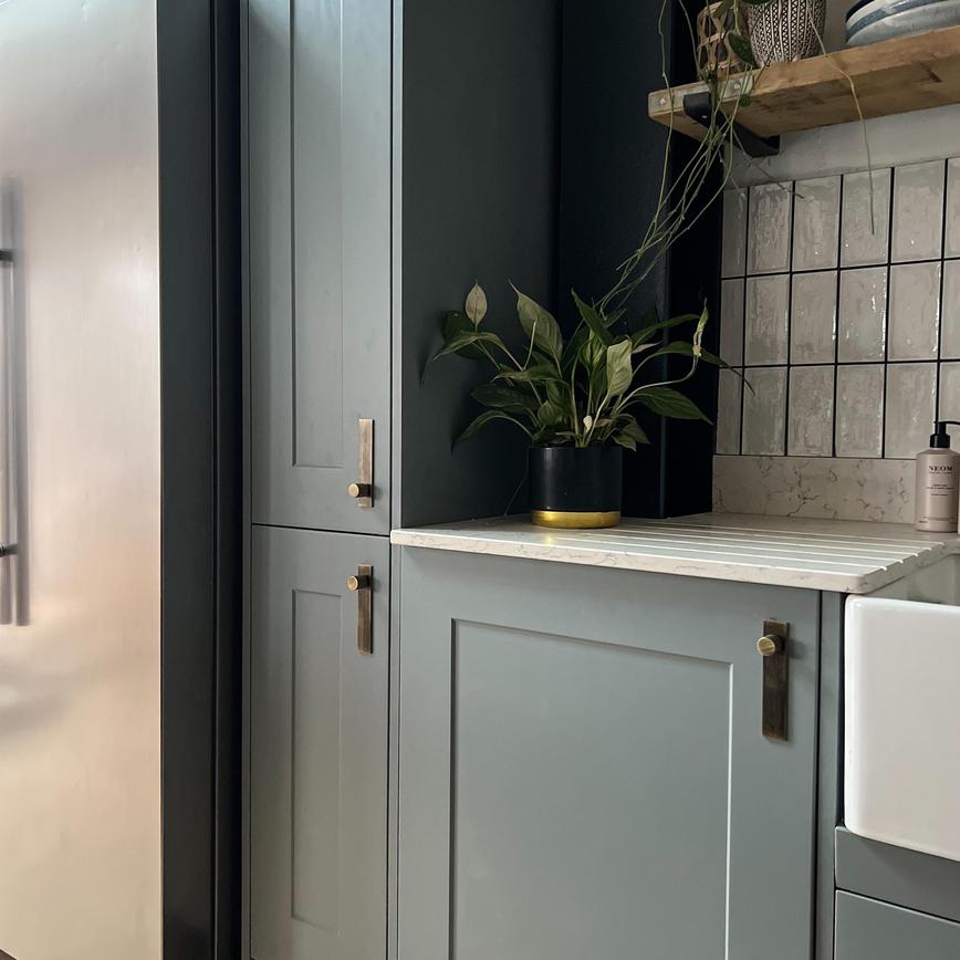 Dusk blue shaker wall cabinets with a tower unit, white ceramic sink, white quartz worktop and American fridge freezer.