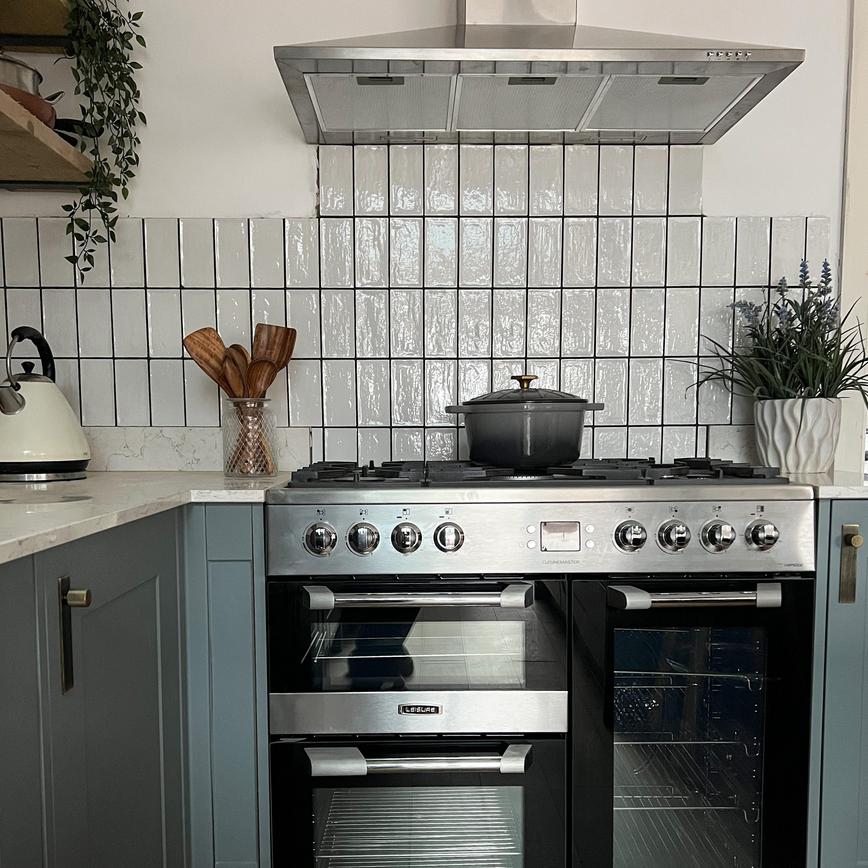 Dusk blue shaker kitchen idea with a black and silver range cooker, white subway tiles, and a silver chimney extractor fan.