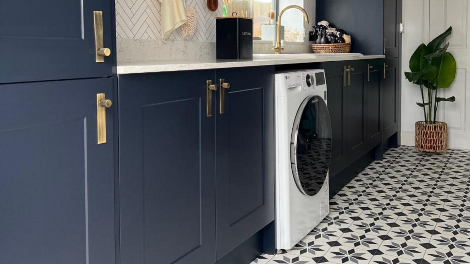 Navy-blue utility room with shaker units. Seen from the kitchen-diner with dusk-blue units with brass handles and backplates.