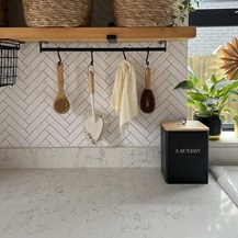 A slim, white, quartz worktop and upstand with a marble-effect pattern and glossy finish for a luxurious utility room idea.