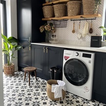 On-trend utility room idea using navy shaker units, white quartz worktops, brushed-brass handles and rectangular backplates.