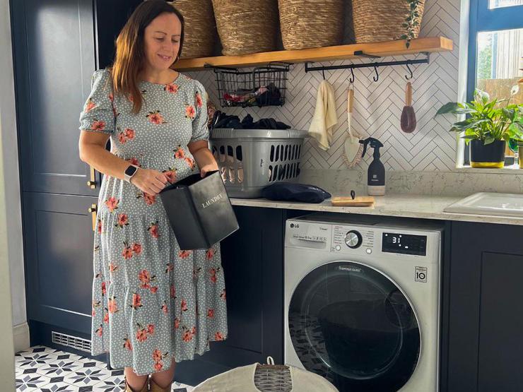 Mel Boyden in her navy utility room. Includes classic shaker units, white worktops, brass handles, and oak open shelving.