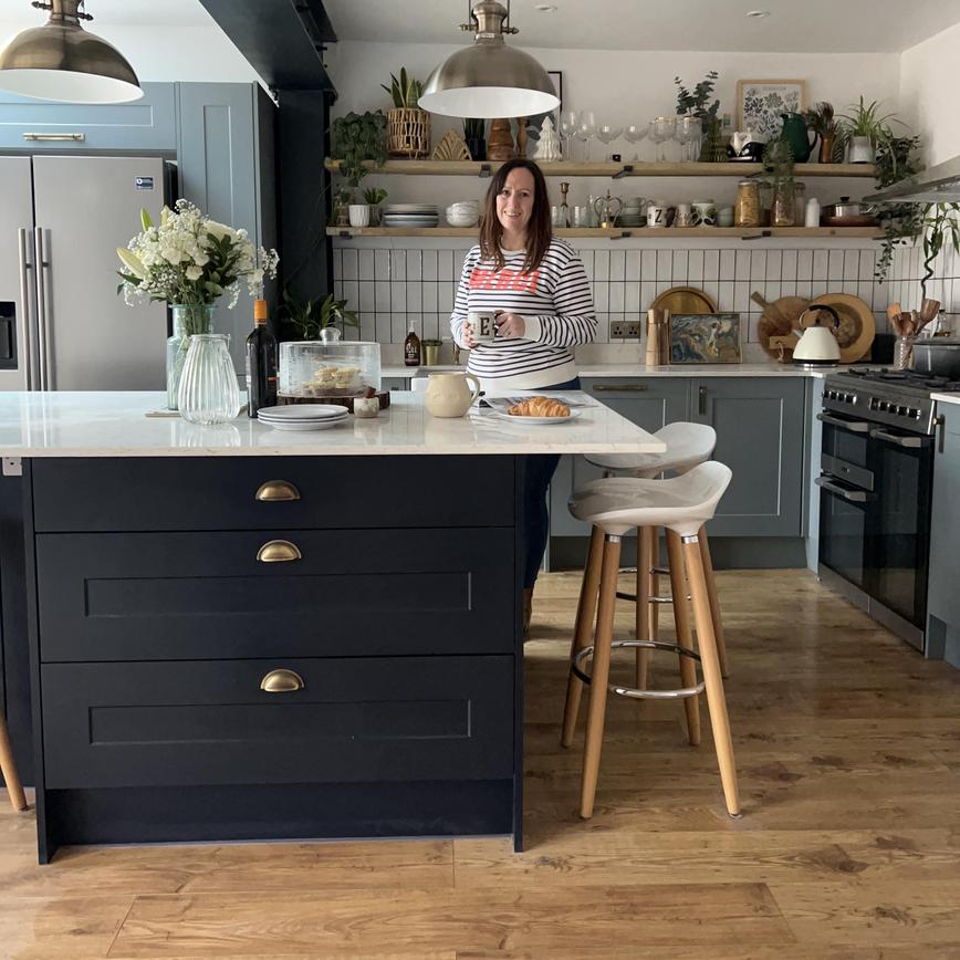 Mel Boyden in finished kitchen featuring navy and dusk-blue shaker cupboard doors and white worktops.