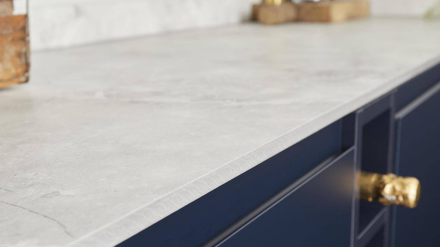 White laminate worktop with a marble-effect pattern, fitted onto navy kitchen cabinets.