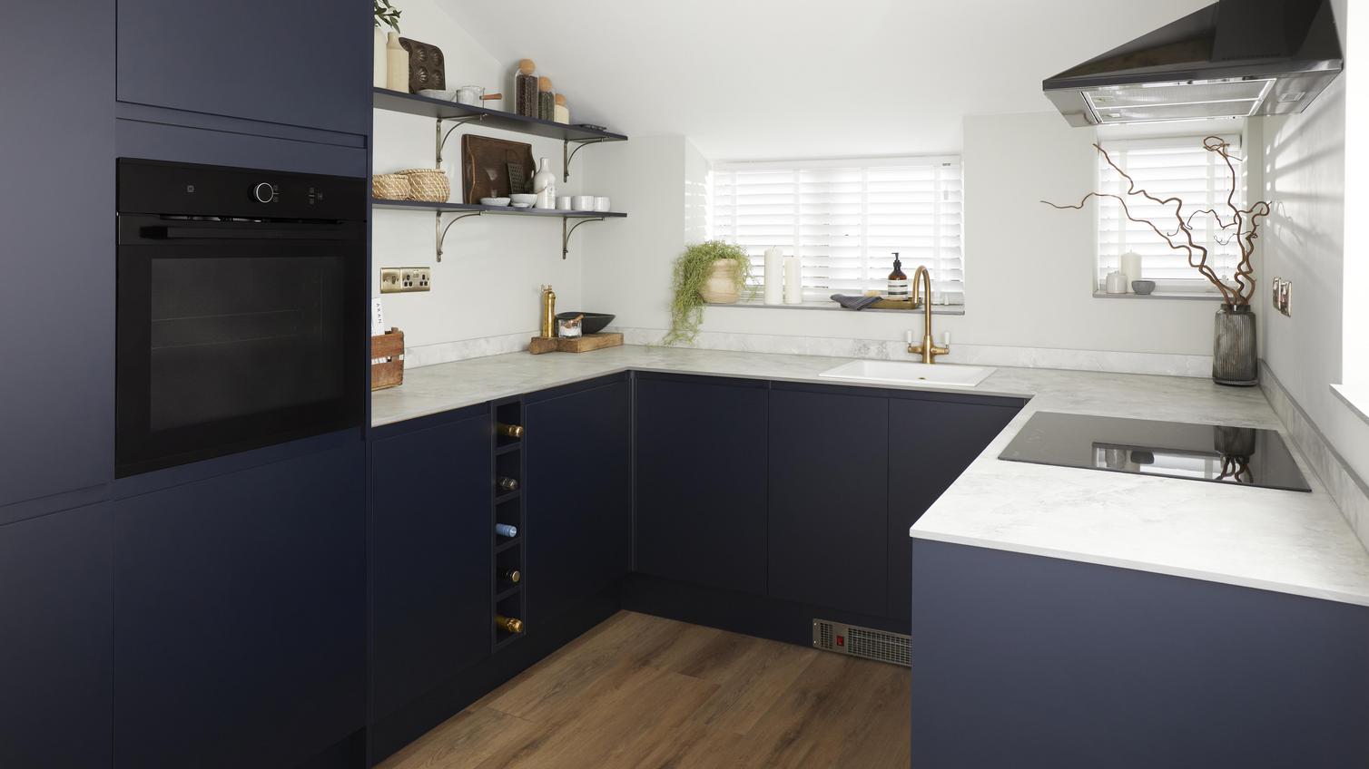 U-shaped navy kitchen, with white marble-style laminate worktop and integrated appliances.