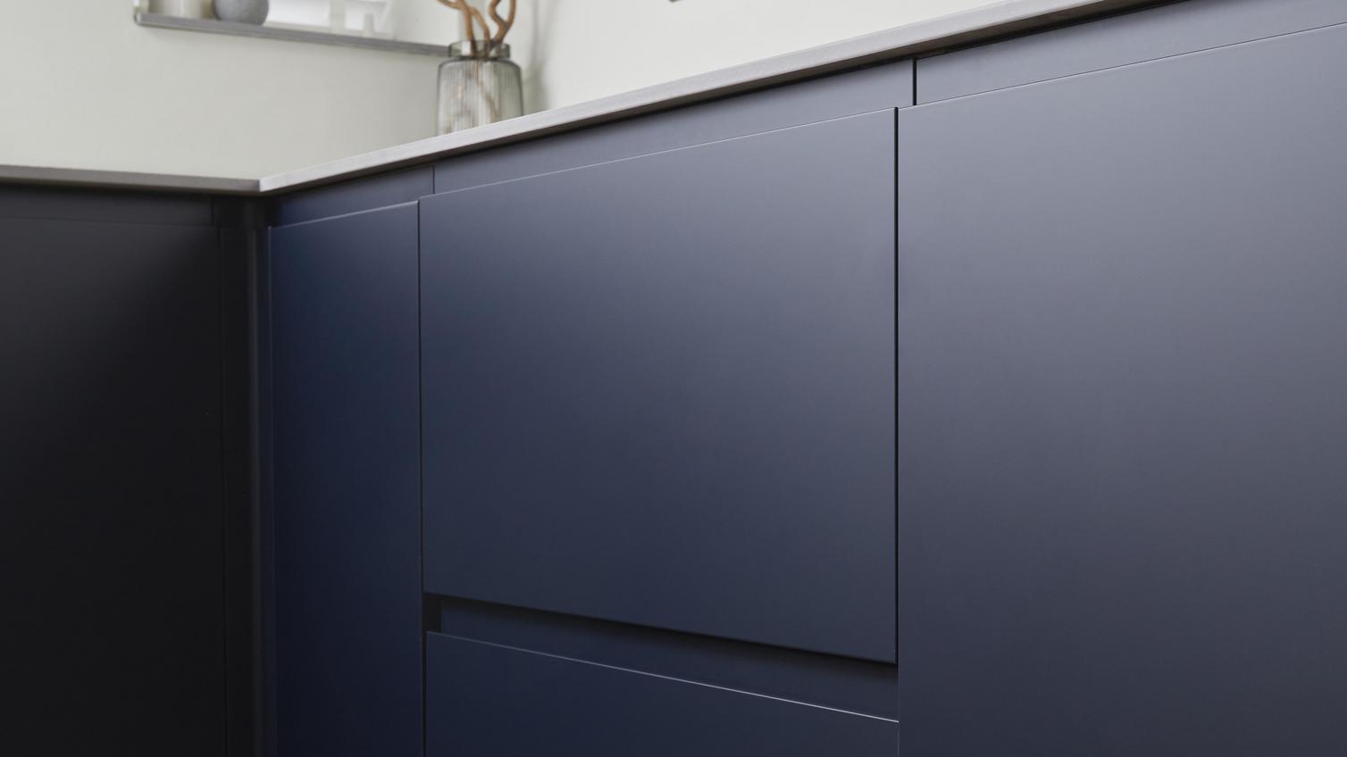 Clerkenwell matt door and drawer fronts, finished in a navy colour and integrated handle design. Also includes oak flooring.