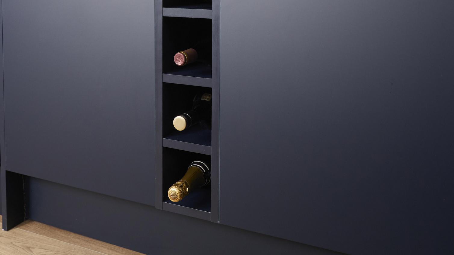 A slim wine rack, which is in a navy matt finish alongside matching kitchen doors. The rack holds 5 bottles of wine.