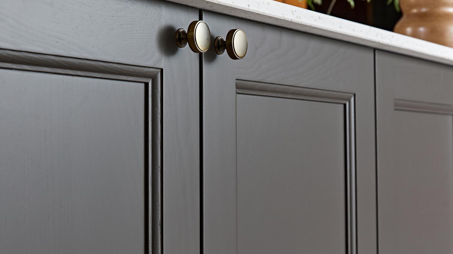 Shaker kitchen doors with a grained finish and a truffle-toned brown colour. It also has round, brass cabinet knobs.