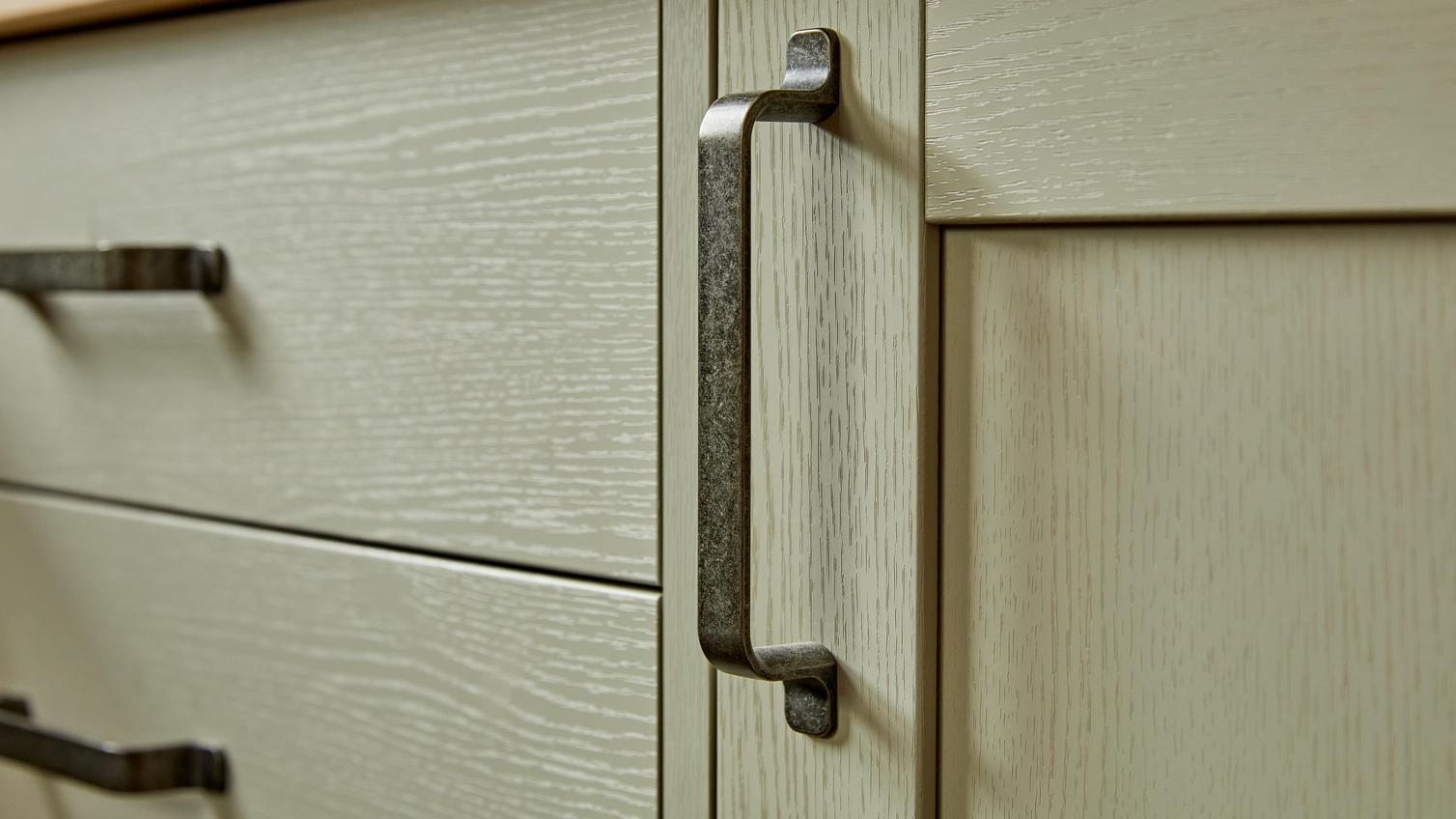 Black, D-shaped handle with a weathered finish fitted on sage-green, shaker doors for a traditional look.