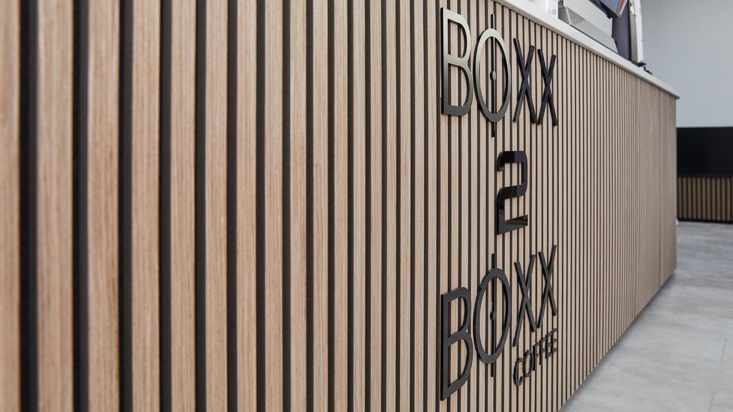 Jill Scott Cafe Kitchen Makeover with oak, acoustic wall panelling on the counter area. Features cafe signage and tile floors.