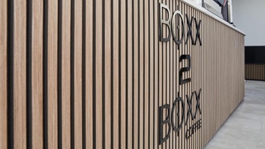 Jill Scott Cafe Kitchen Makeover with oak, acoustic wall panelling on the counter area. Features cafe signage and tile floors.