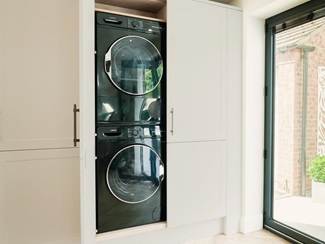Two laundry machines stacked up inside a singular cupboard