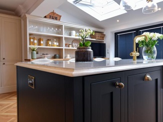A black kitchen island in a shaker, in-frame style with a bespoke quartz worktop.