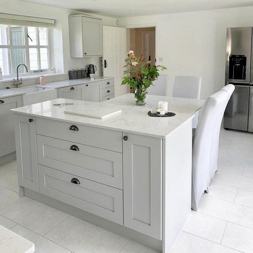 A premium grey kitchen idea featuring solid timber shaker units in dove grey. Includes white worktops, floors, and a sink.