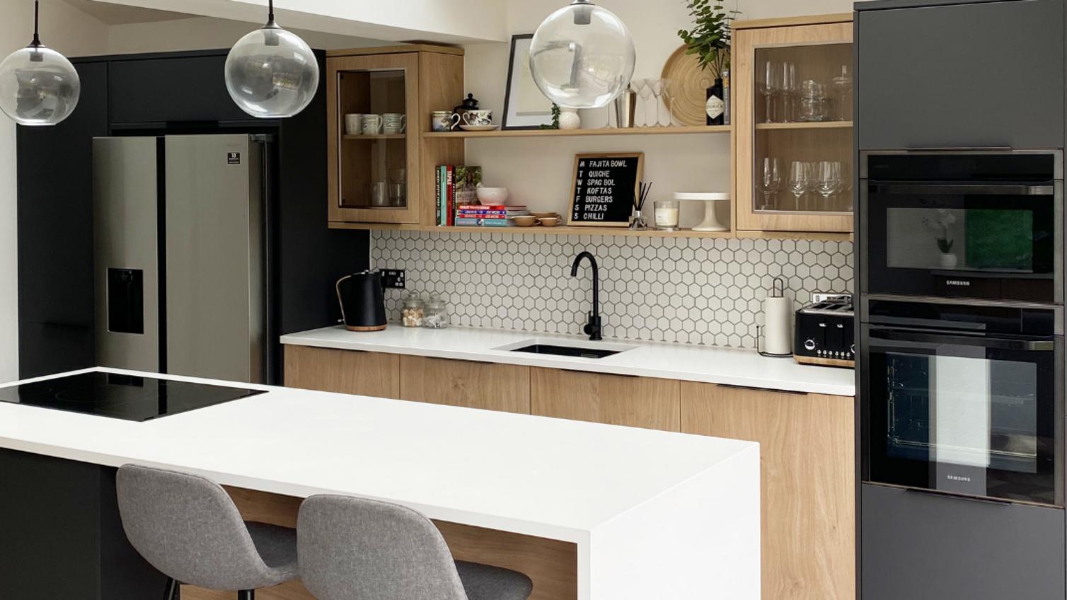 Modern oak kitchen idea using oak and black slab kitchen doors. Includes white worktops, an undermount sink, and black tap.