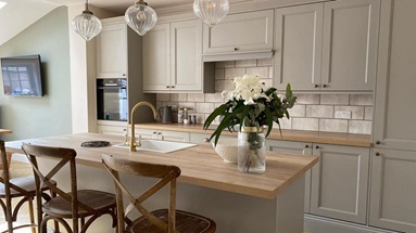 A rustic kitchen idea with shaker cupboards, solid wood worktops, herringbone flooring, and knob handles in an island layout.
